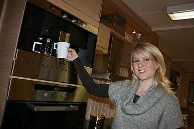 Interiørdesigner og kundekontakt Gøril Åmot viiser Fossline Norform-kjøkkenets hypermoderne kaffetrakterløsning. Foto: Marit Mjøen