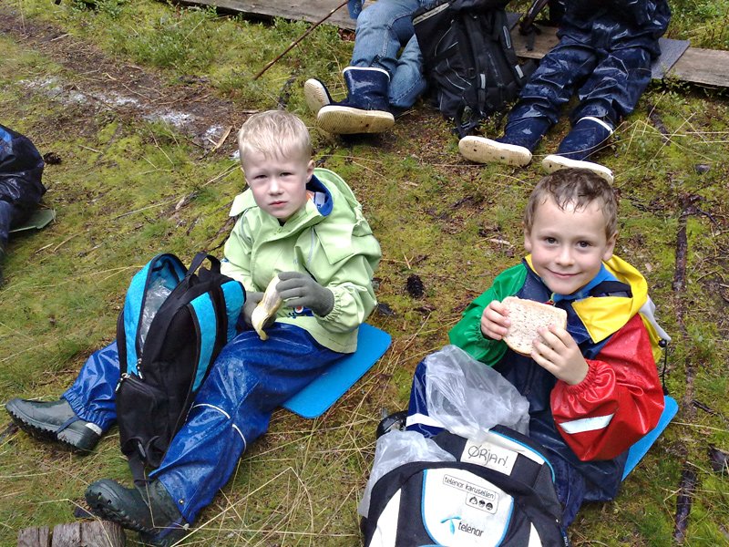 Olav og Ørjan tar matpause. Humøret er på topp, selv om kakskiva står i fare for å bli våt.  